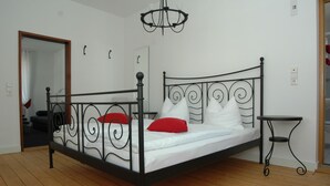 A bedroom with a metal bed frame, white bedding, and a small side table. - Hotel Scheffelhof (Waldkirch)