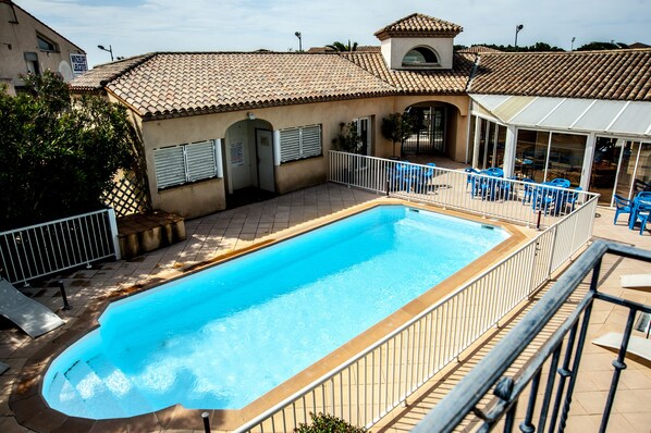 Una piscina al aire libre de temporada, sillones reclinables de piscina