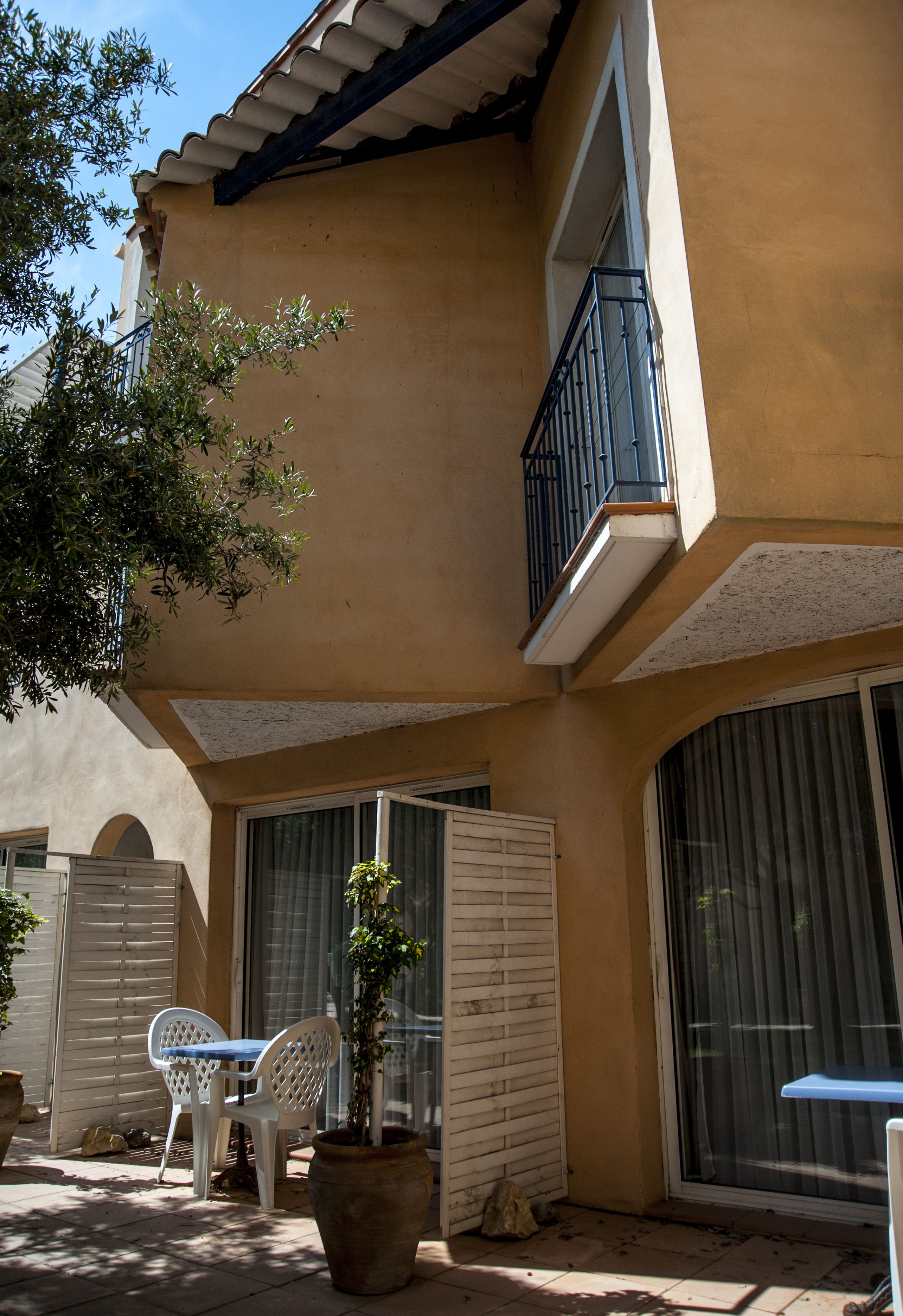 A building with a balcony, large windows, and a potted plant.