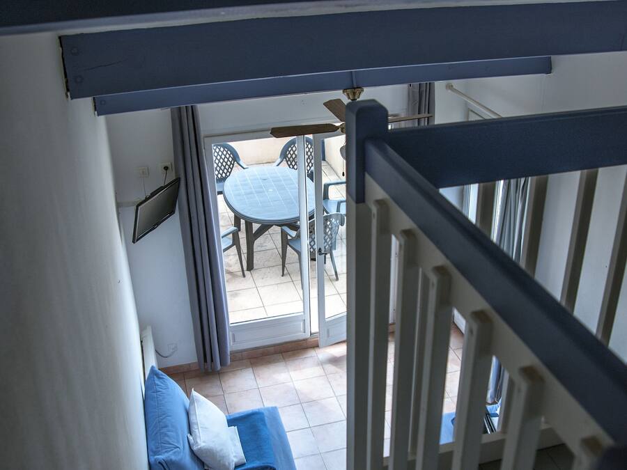 Eine Treppe führt zu einem Balkon mit einem blauen Sofa und einem Tisch.