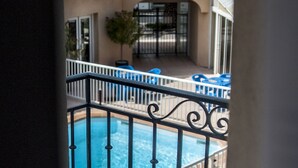 A pool area with a tiled roof, a small garden, and a gate. - Hôtel Leukos (Leucate)