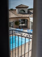 Un área de piscina con techo de baldosas, un pequeño jardín y una reja.