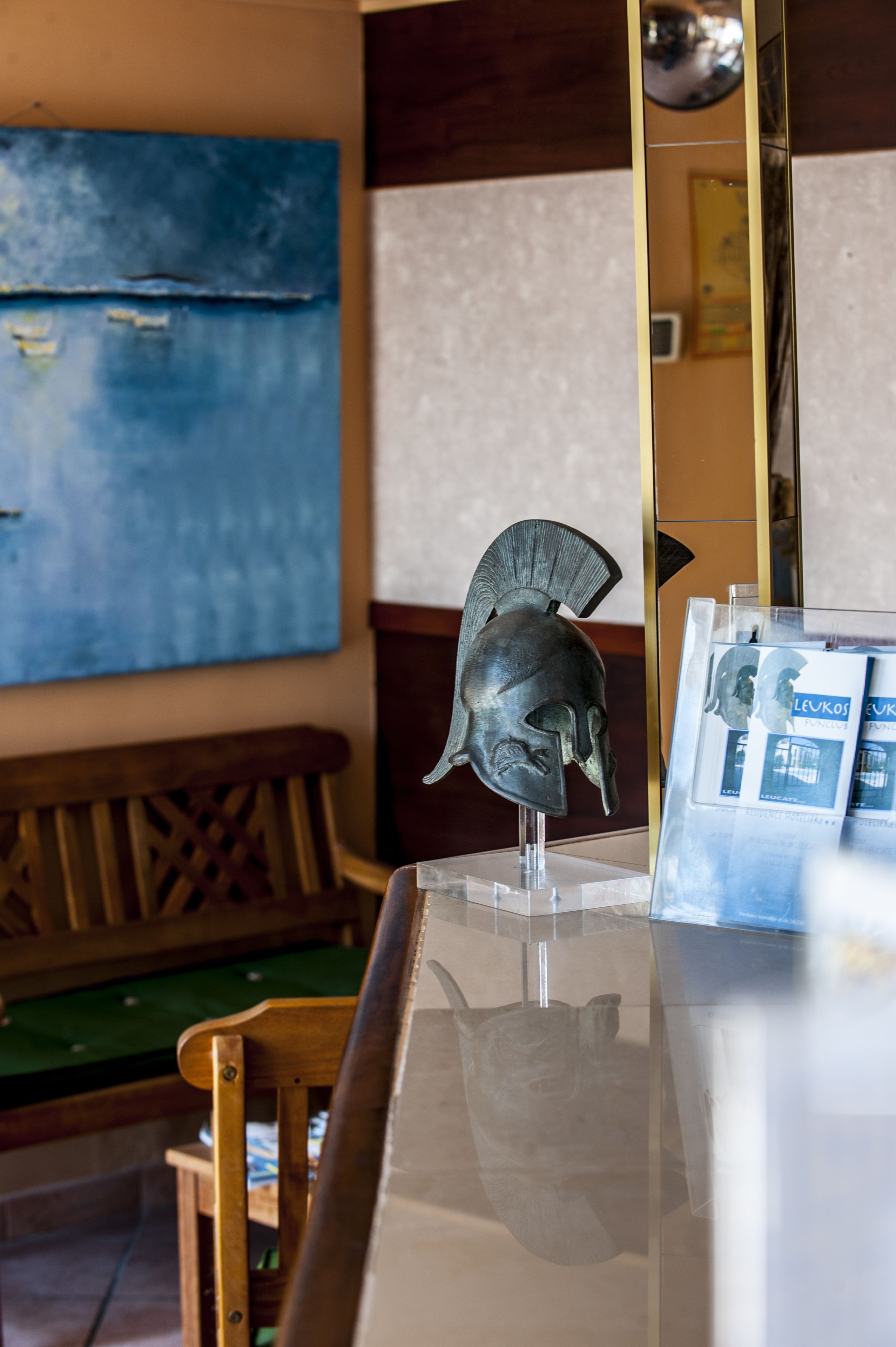 Ein Zimmer mit Holzstuhl, Tisch und einem großen Spiegel, der einen Helm reflektiert.