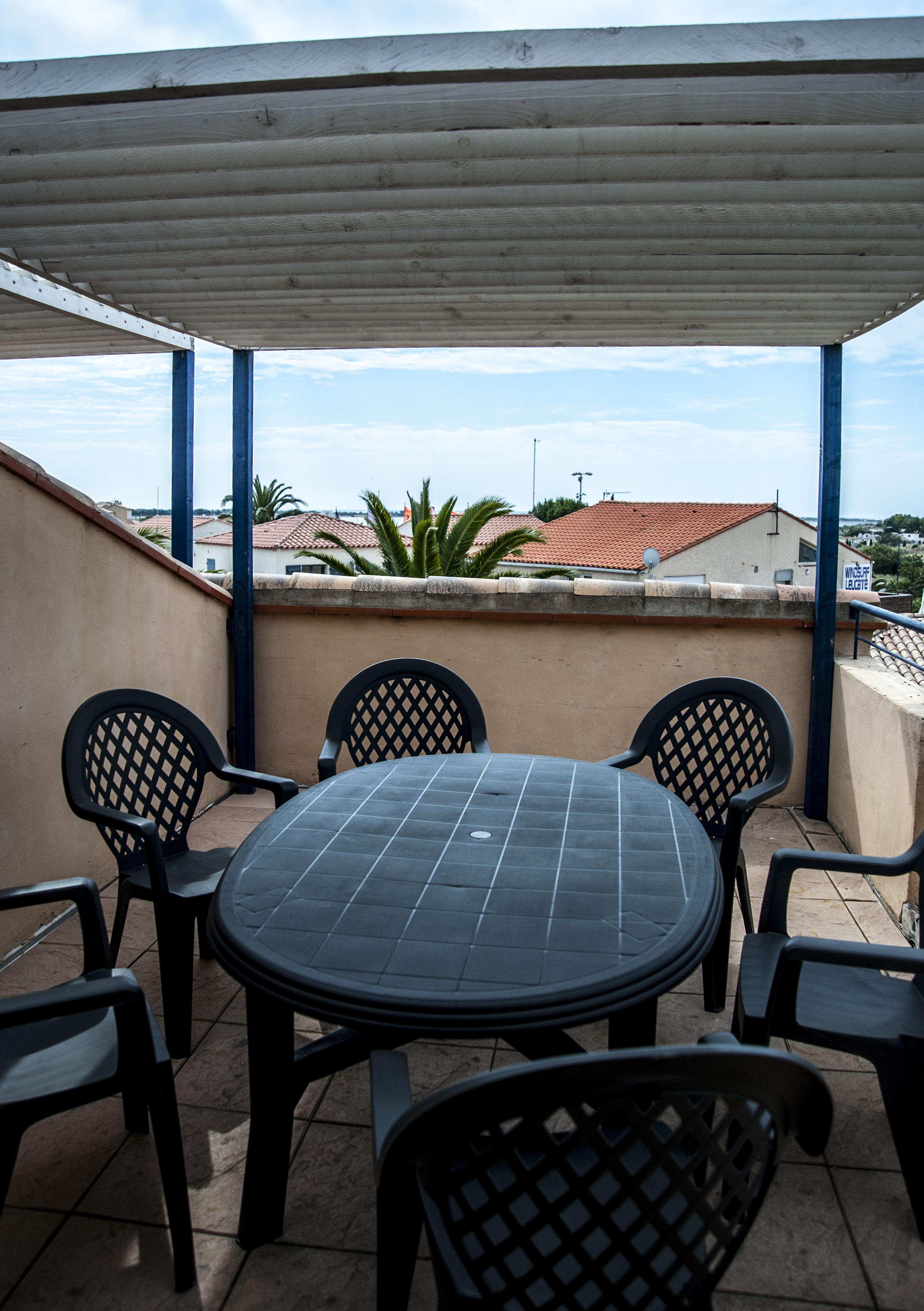 Une terrasse extérieure couverte, avec une table ronde et six chaises.