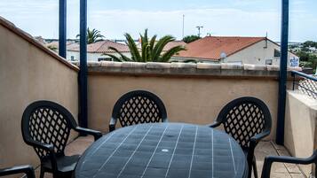A covered outdoor patio with a round table and six chairs.