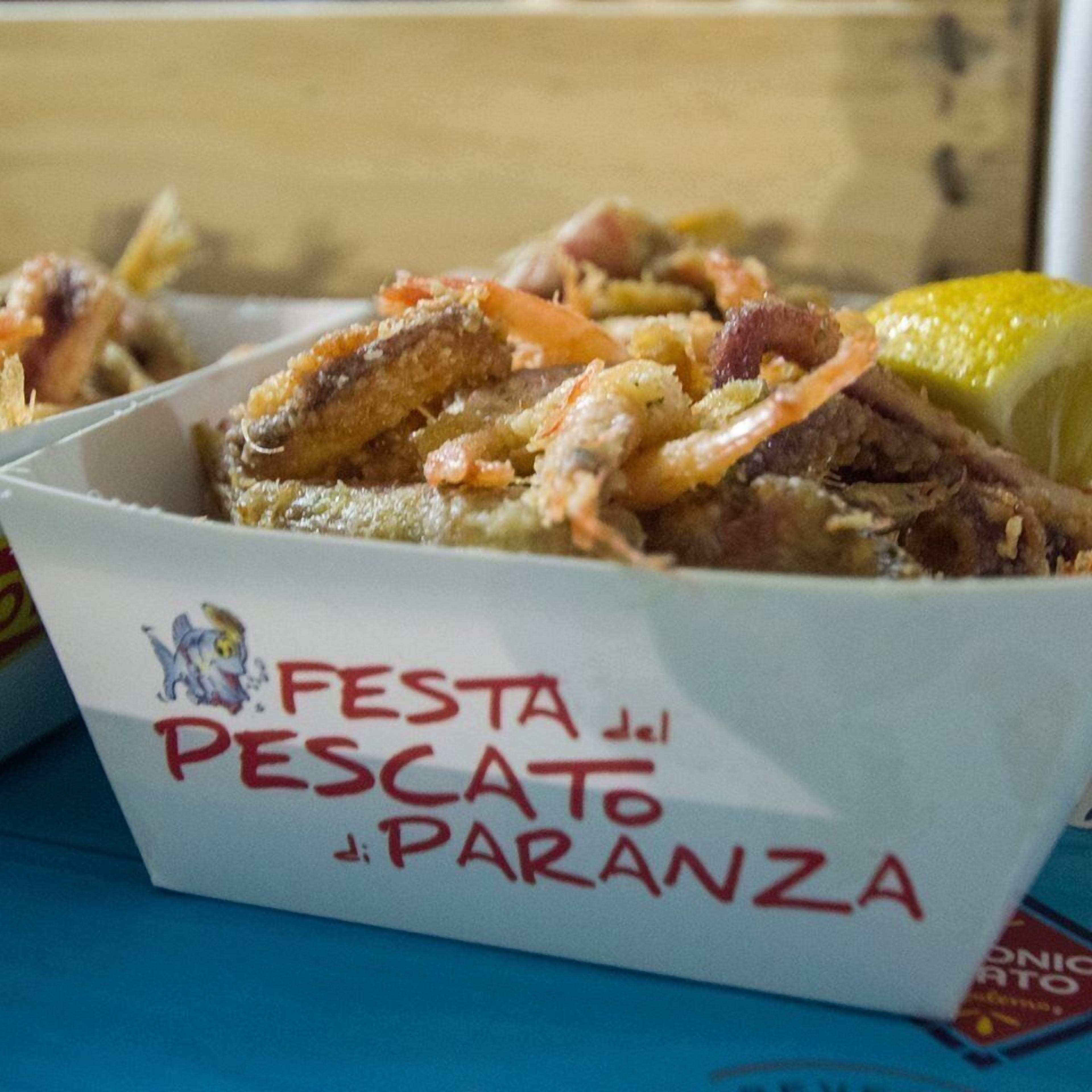 A food container labeled "FESTA del PESCATO de PARANZA" with a variety of seafood dishes.