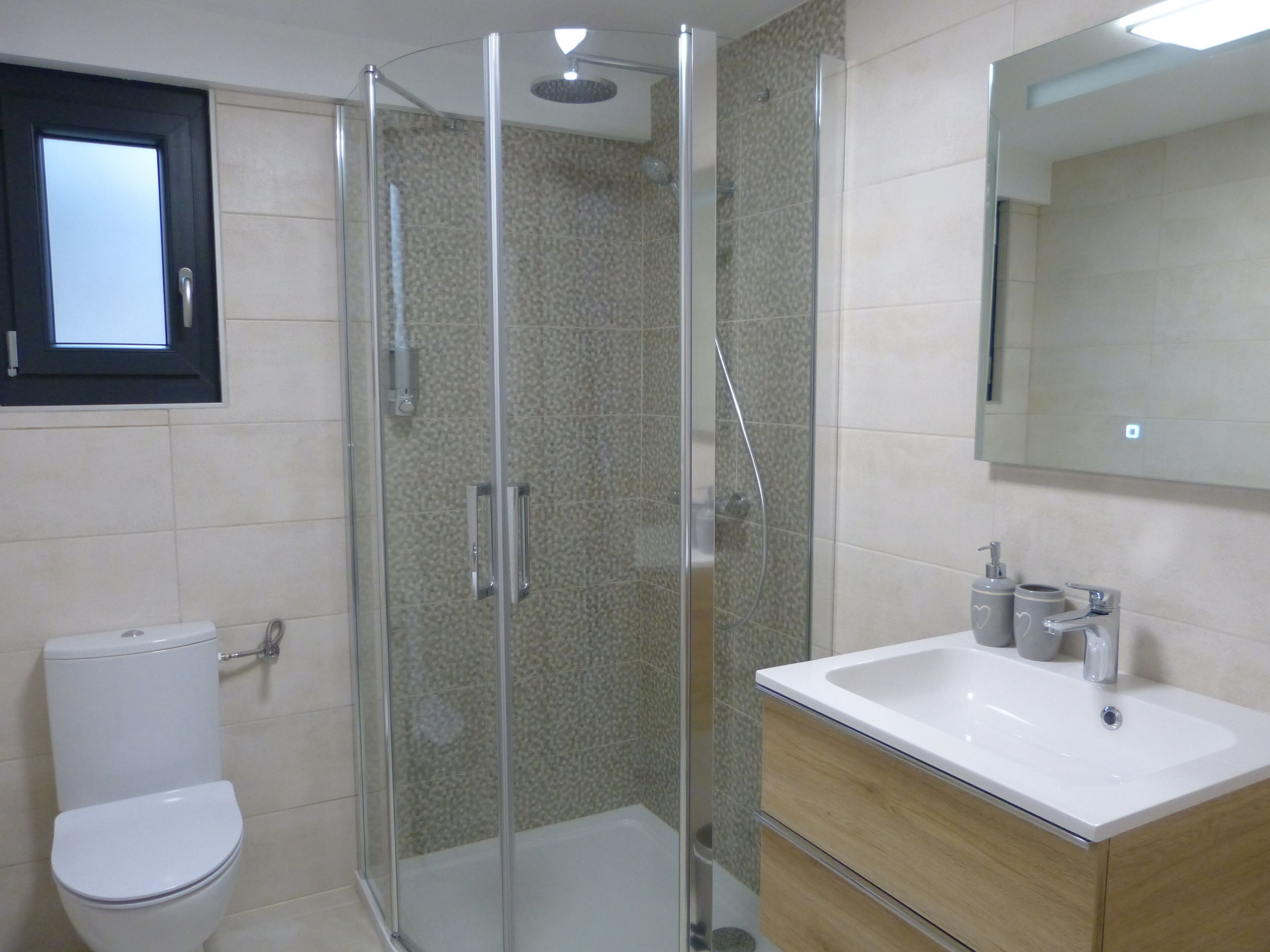 Une salle de bain avec une douche à parois de verre, des toilettes et un lavabo avec un miroir au-dessus.