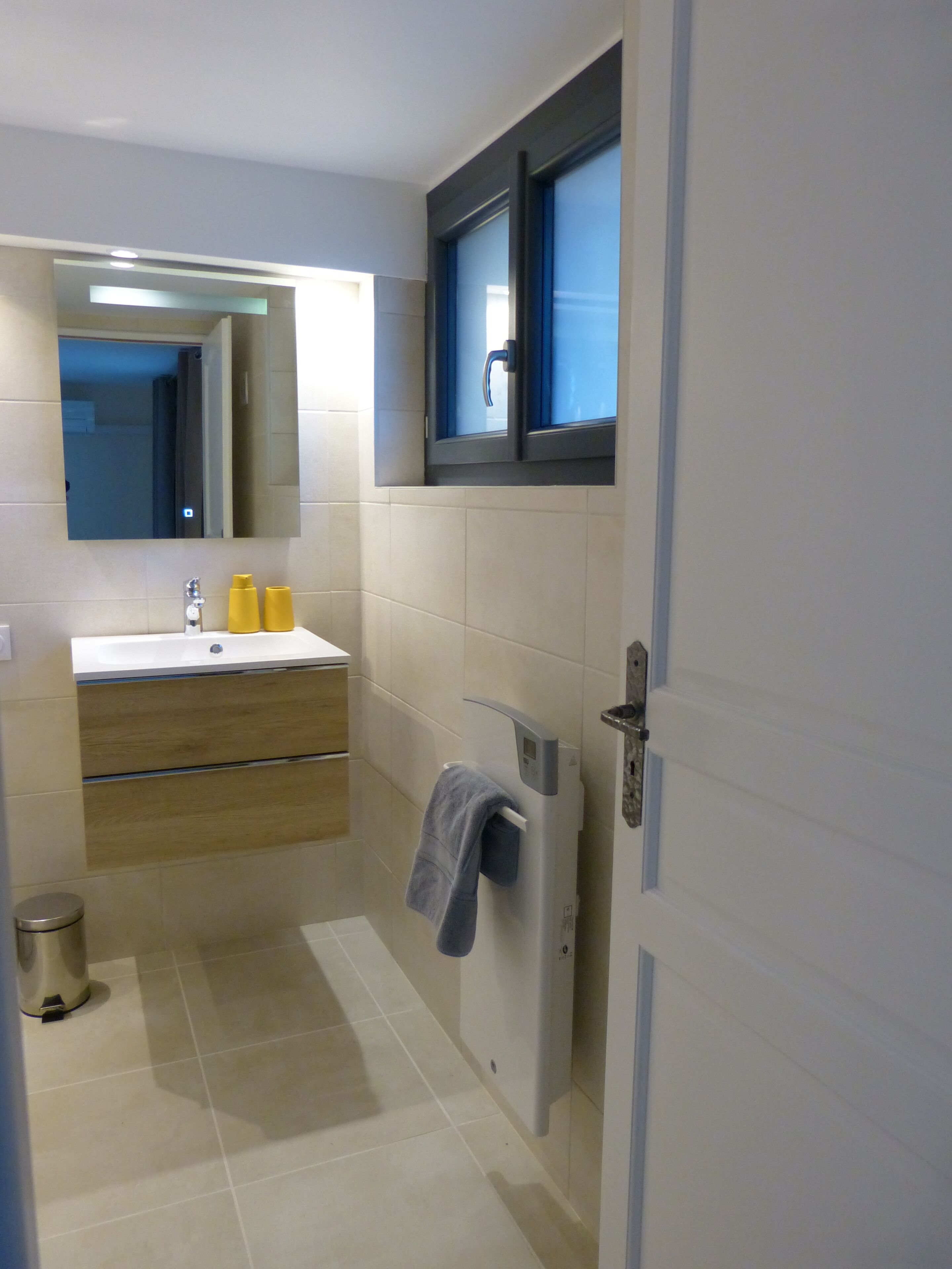 Ein modernes Badezimmer mit Waschbecken, Spiegel und Handtuchhalter.
