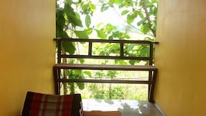 A room with a wooden bench, a small table, and a view of greenery through a window. - Romsiri Resort (Sung Noen)