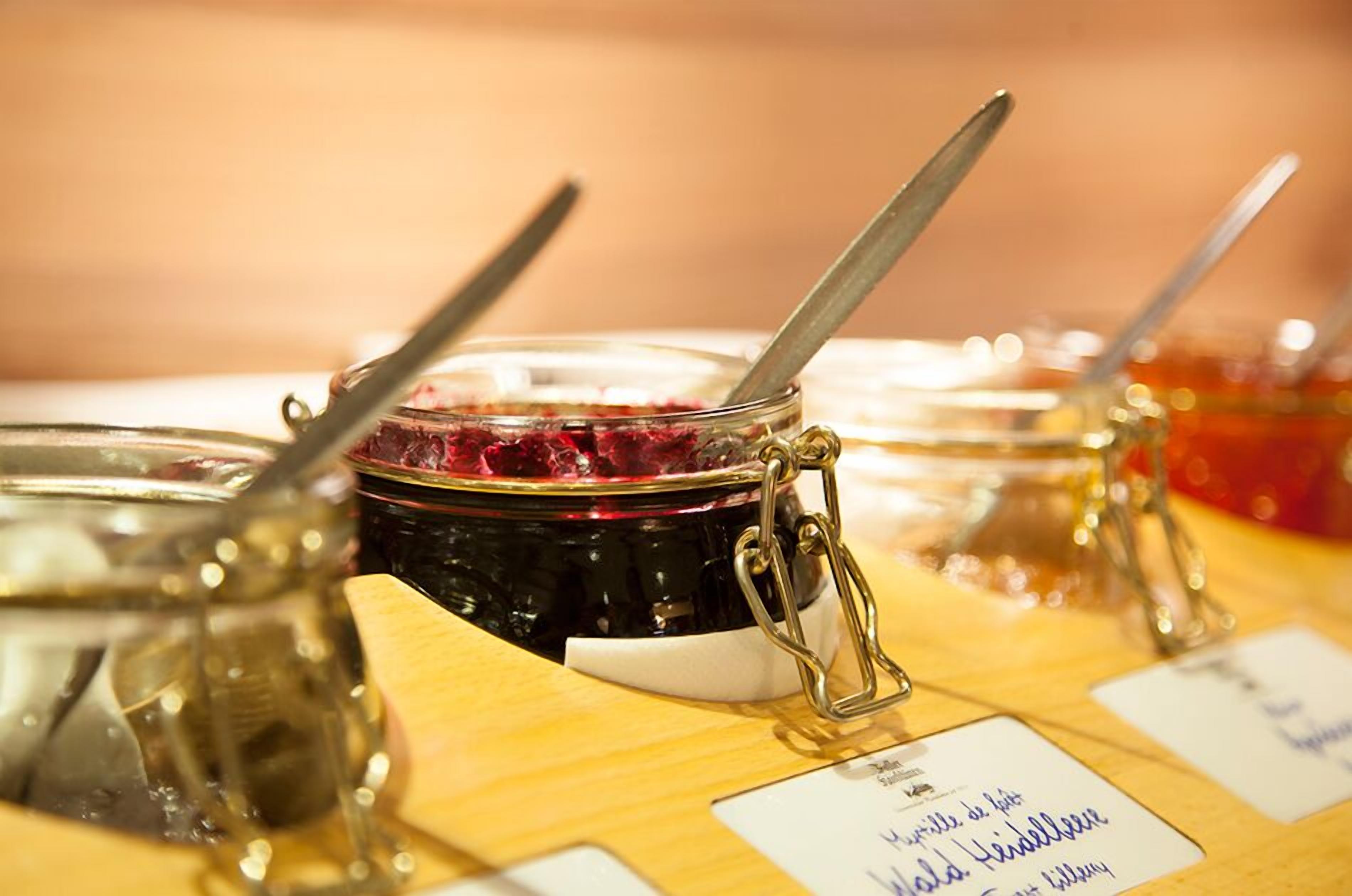 Una mesa con frascos de mermelada, cada uno con etiqueta y cuchara.