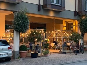 An outdoor seating area with tables and chairs, a greenhouse structure, and potted plants. - Hotel-Restaurant Poststuben (Bensheim)