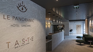 A modern hotel lobby with a reception desk, seating area, and a bar named "TASTE". - Le Panoramic Hôtel (Sancerre)
