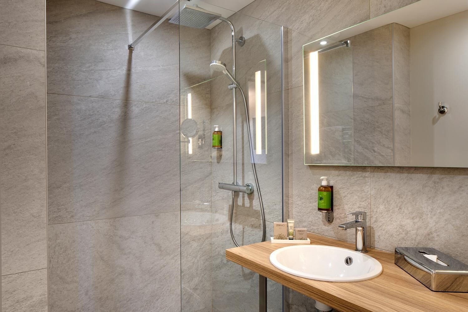 A modern bathroom with a glass-enclosed shower, a wooden vanity, and a large mirror.