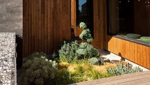 A modern building with a concrete facade, wooden slats, and a landscaped garden area. - Le Panoramic Hôtel (Sancerre)