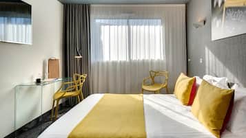 Une chambre d’hôtel comprenant un lit, un bureau, deux chaises, une grande fenêtre avec des rideaux et une œuvre d’art accrochée au mur.