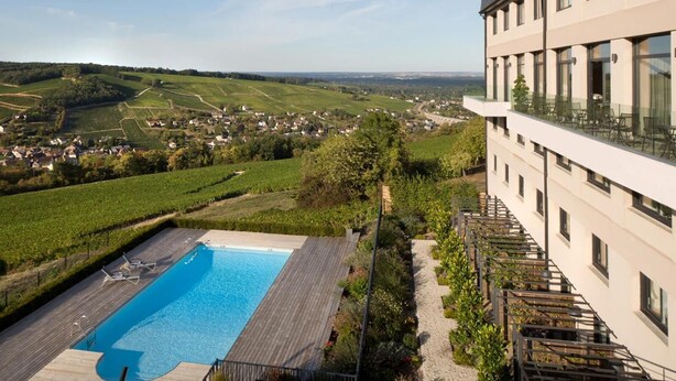 A hotel with a pool, surrounded by greenery and vineyards, overlooking a valley. - Le Panoramic Hôtel (Sancerre)
