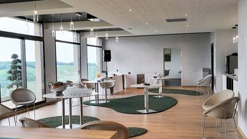 A modern living room with large windows, a dining area, and a kitchen.