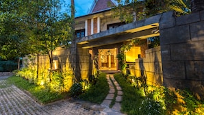 A traditional house with a stone wall entrance, a tiled pathway leading to the door, and lush greenery surrounding the property. - Charming Angkor Resort & Spa (Siem Reap)