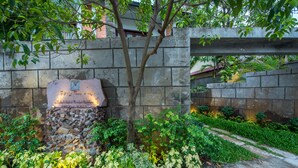 A stone wall with a plaque, lush greenery, and a pathway. - Charming Angkor Resort & Spa (Siem Reap)