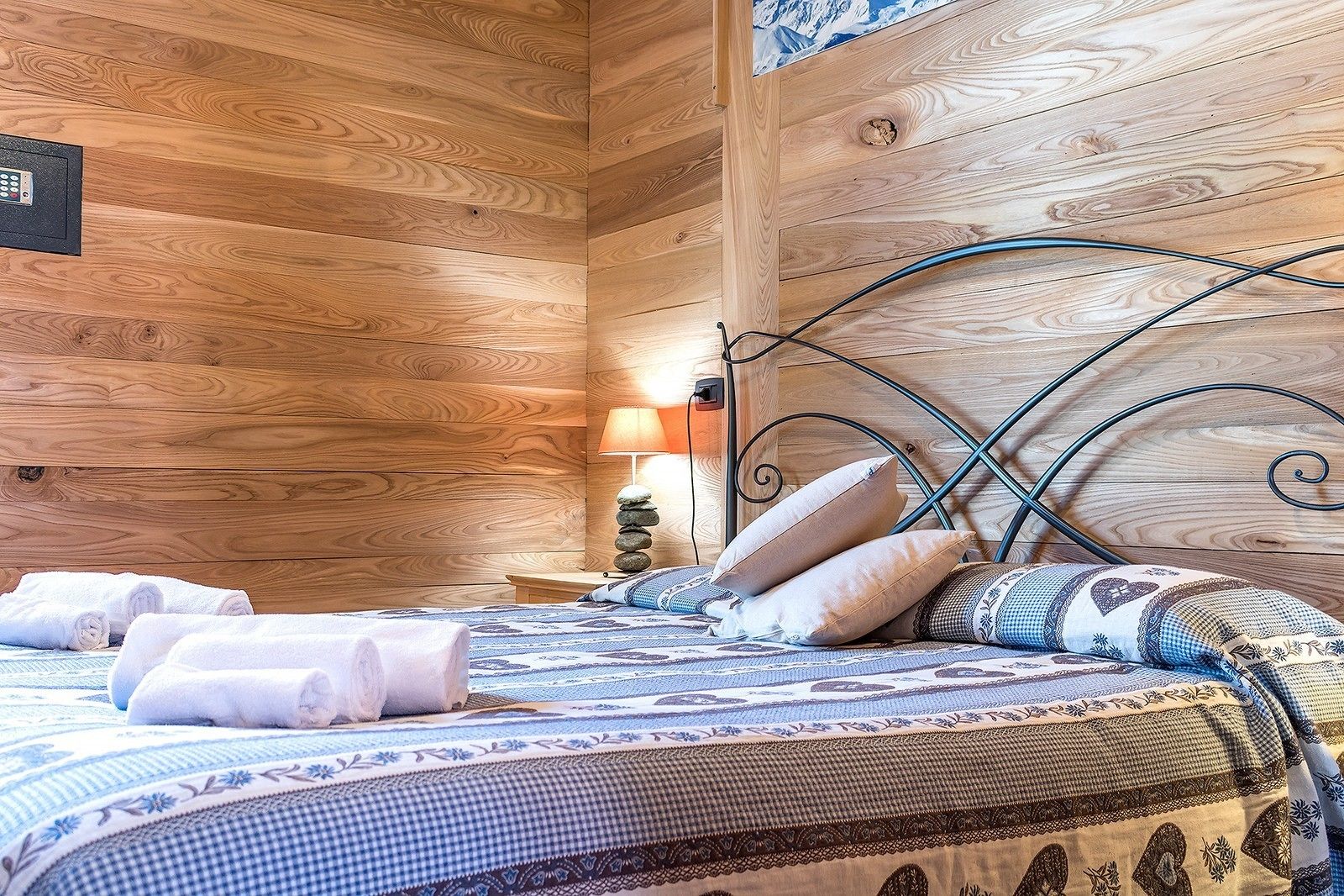 A wooden cabin-style room with a bed, pillows, and a nightstand with a lamp.