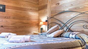 A wooden cabin-style room with a bed, pillows, and a nightstand with a lamp.