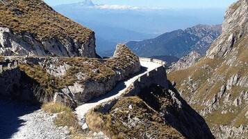 Un sentiero montano impervio con terreno roccioso e vegetazione rada.