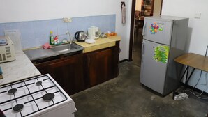 A compact kitchen with a gas stove, sink, and a refrigerator. - prasad suomi villa (Matara)