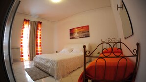 A bedroom with a bed, a nightstand, a painting, and a window with curtains. - The Last Floor (Torre del Greco)