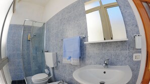 A bathroom with a glass shower enclosure, a toilet, a bidet, a sink, and a mirror. - The Last Floor (Torre del Greco)