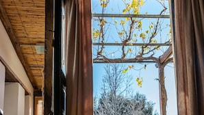 A wooden chair and table inside a room with a view of a garden and trees outside.
