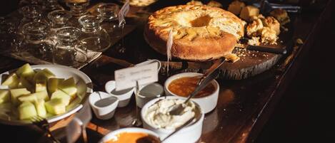 A buffet table with various food items including a large cake, bowls of fruit, and different sauces.