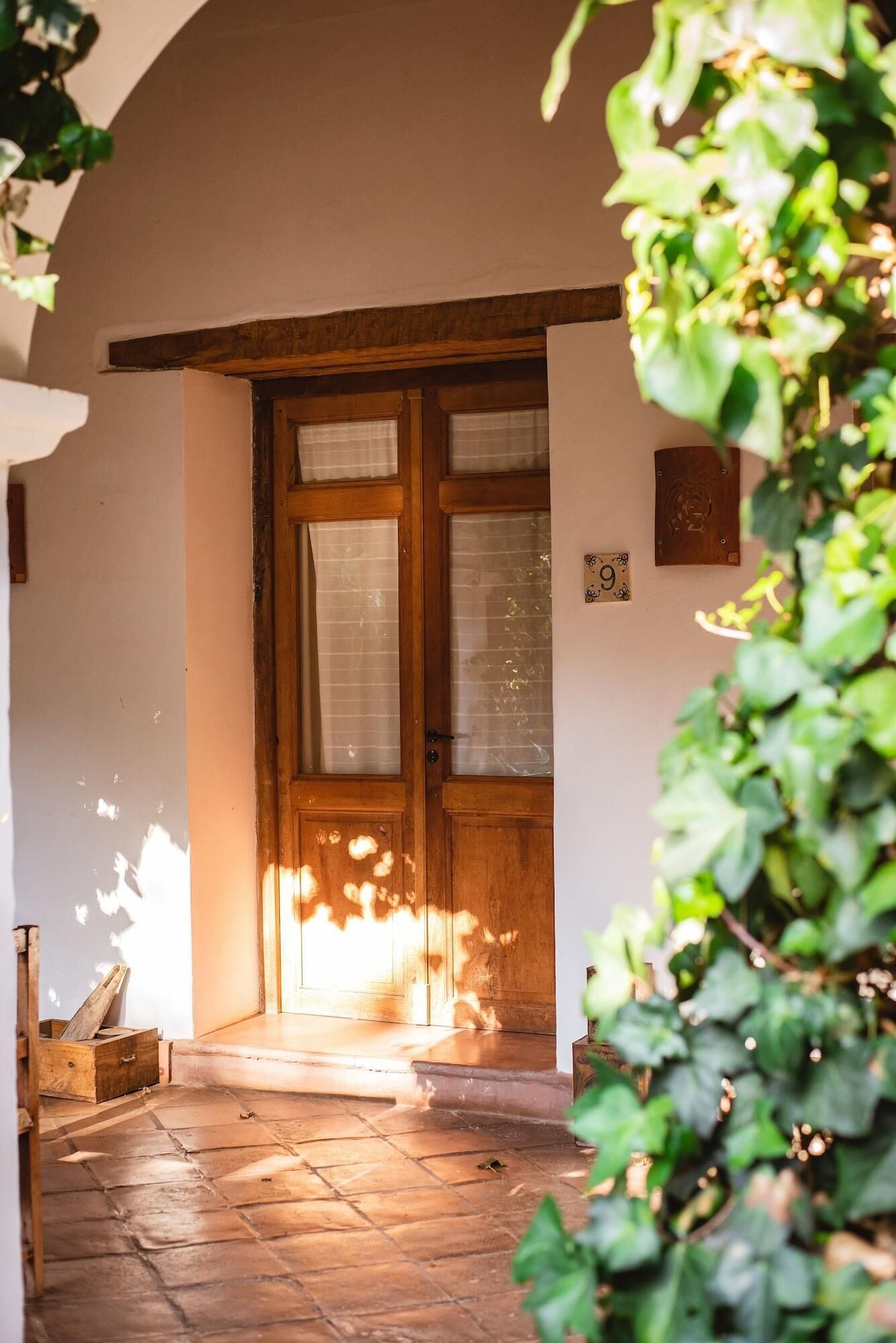 A wooden door with frosted glass panels, a stone-paved entrance, and a small wooden box on the left.