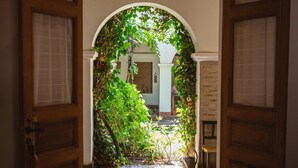 An open doorway leading to a courtyard with a bed in the foreground.