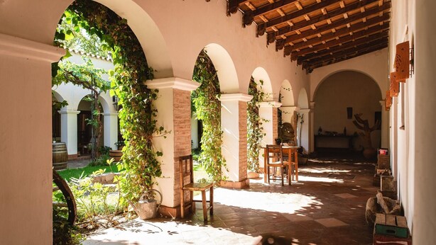 An outdoor covered patio with arches and greenery.