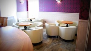 A hotel room with a round wooden table, two white armchairs, and a small round table with an orange top. - The Aberlour Hotel (Aberlour)