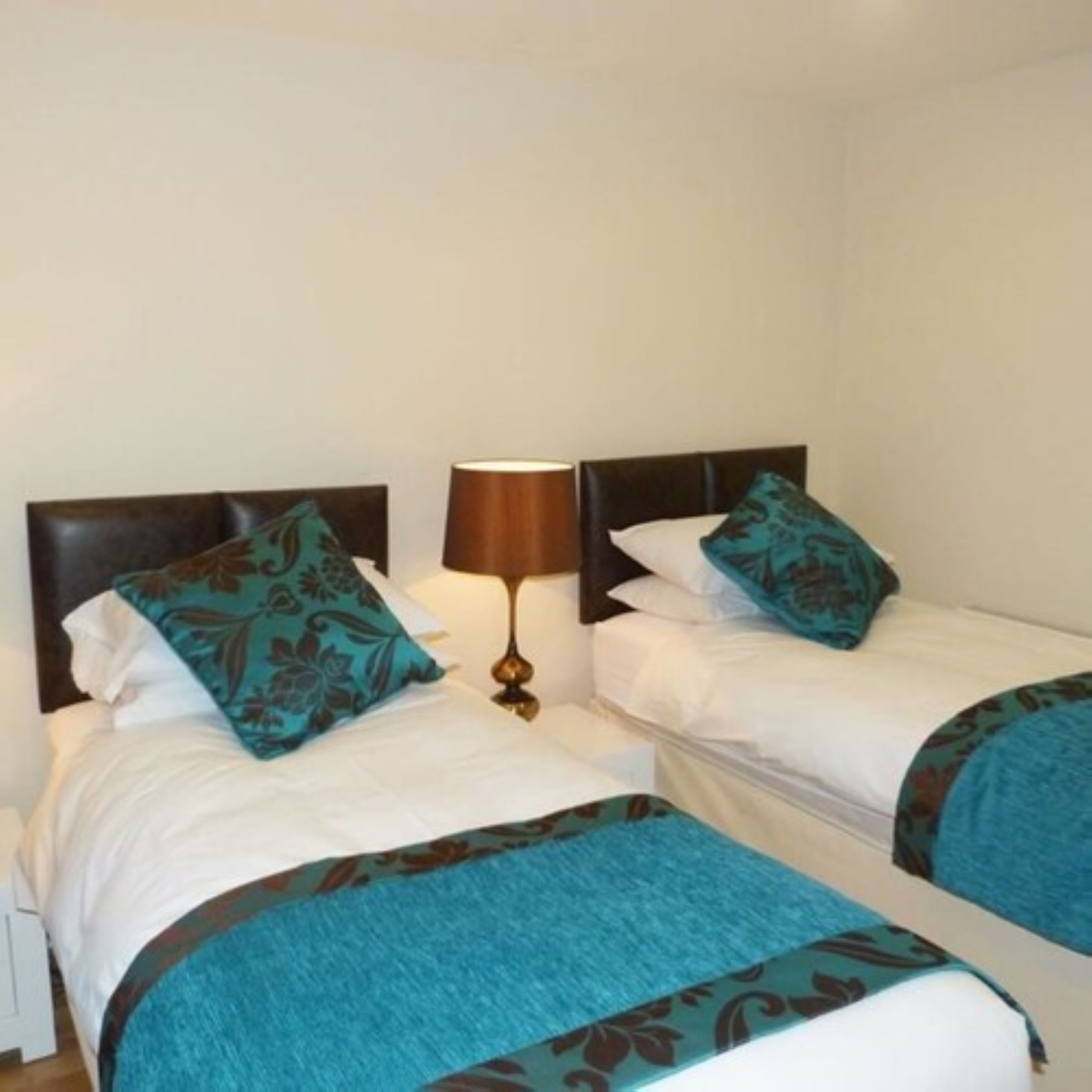 Habitación de hotel con dos camas, cada una con un cabecero y almohadas a juego.