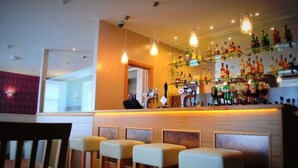 A bar area with a wooden counter, hanging light fixtures, and a variety of bottles. There are four bar stools in front of the counter. - The Aberlour Hotel (Aberlour)