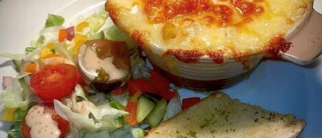A plate with a baked dish, a side salad, and a slice of bread.