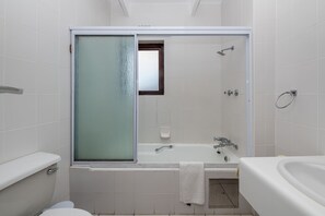 Een moderne badkamer met een douchecabine van glas, een bad en een wastafel.