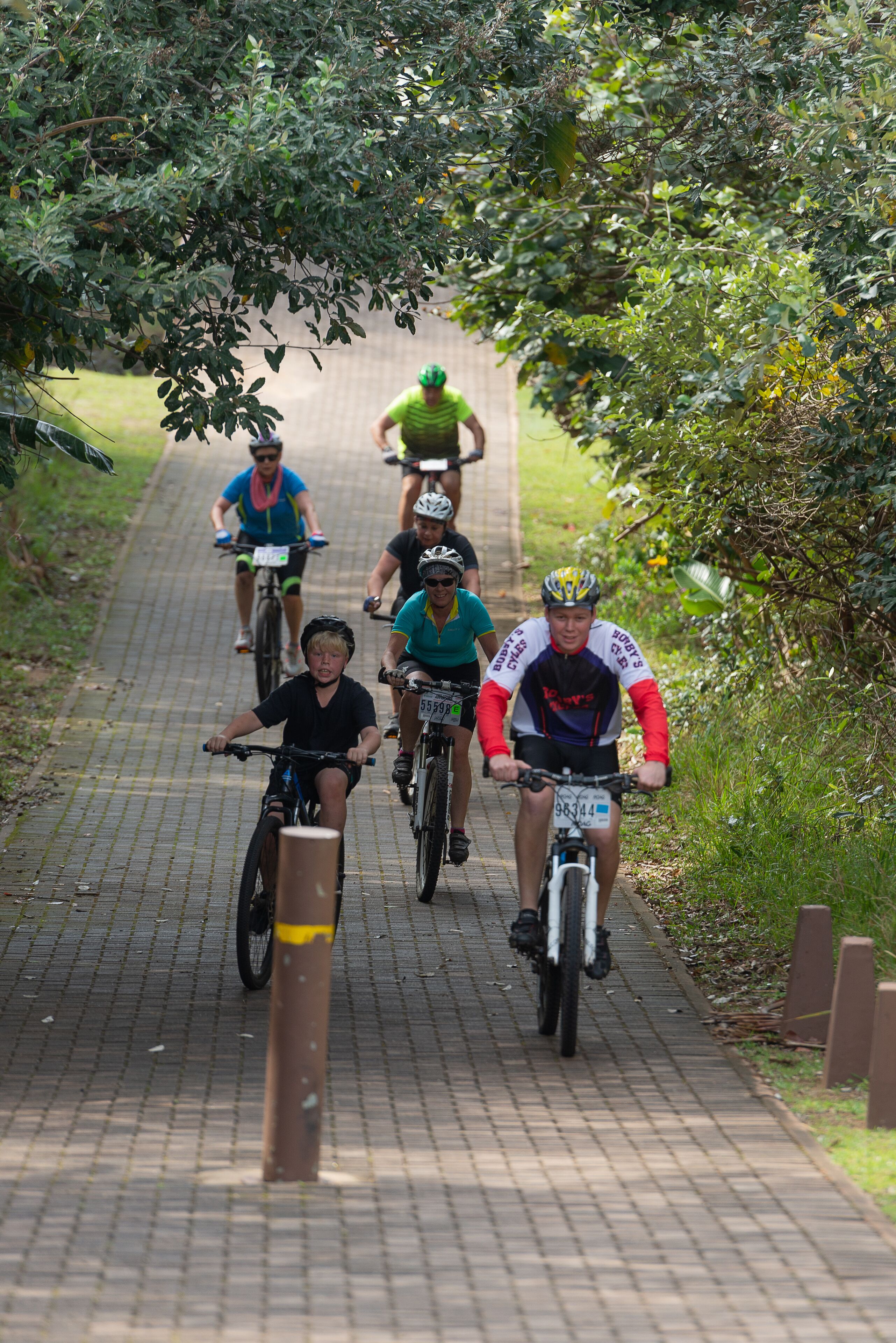 Een groep fietsers op een verhard pad, omringd door groen.