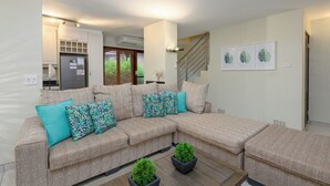 A modern living room with a sectional sofa, two potted plants, and a staircase leading to an upper level. - San Lameer Villa Rentals  3014 (Southbroom)