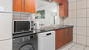 Una cocina moderna con armarios de madera, microondas, cafetera, lavavajillas y un lavabo.