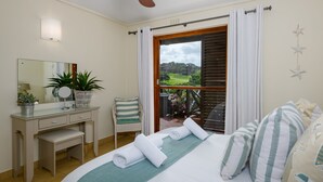 A bedroom with a bed, a desk, a chair, a mirror, and a view of the outdoors. - San Lameer Villa Rentals 2536 (Southbroom)
