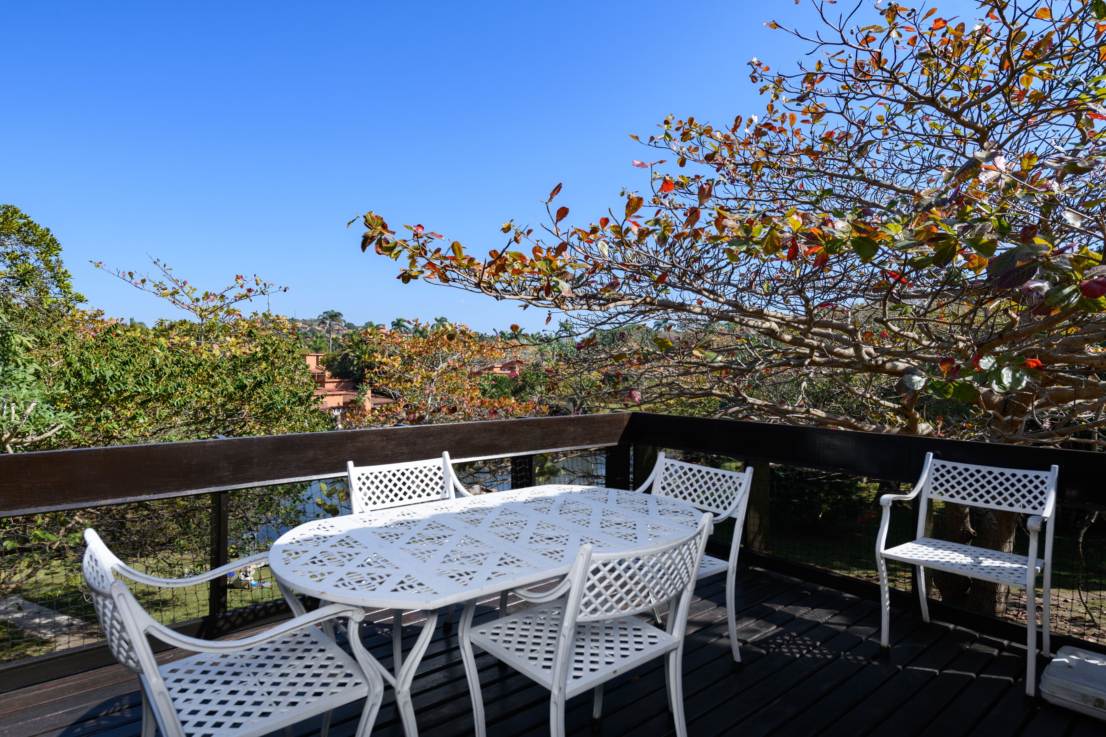 A deck with a round table and four chairs, surrounded by a wooden railing.