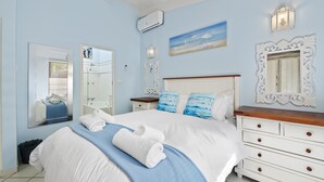 A bedroom with a large bed, a dresser, a mirror, and a painting on the wall. - San Lameer Villa Rentals  2845 (Southbroom)