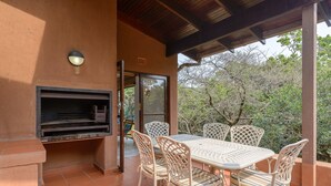 An outdoor patio with a grill, white wicker chairs, and a tiled floor. - San Lameer Villa Rentals 3116 (Southbroom)