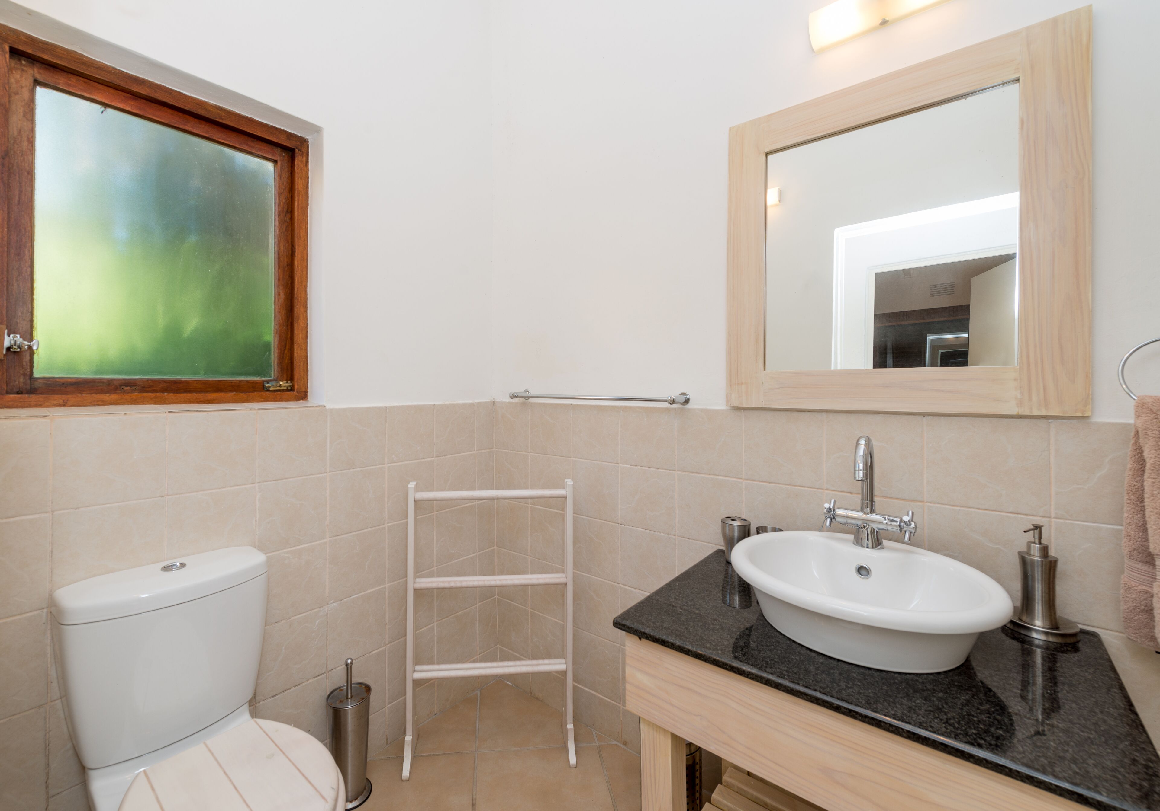 A bathroom with a toilet, sink, mirror, and towel rack.