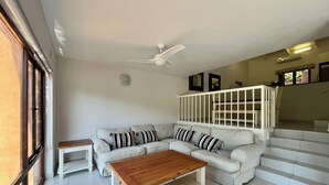 A living room with a white sofa, a wooden coffee table, a white armchair, and a white staircase. - San Lameer Villa Rentals 3511 (Southbroom)