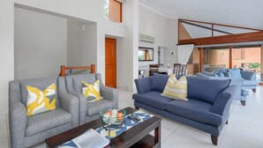 A modern living room with grey and blue sofas, a coffee table, and a glass bowl with oranges. - San Lameer Villa Rentals 13937 (Southbroom)