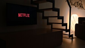 Een moderne trap met een flatscreen televisie waarop in rode letters 'NETFLIX' staat.